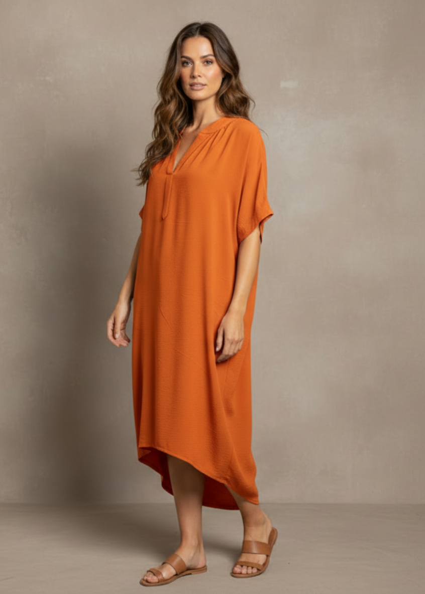 Woman wearing an orange dress against a neutral background