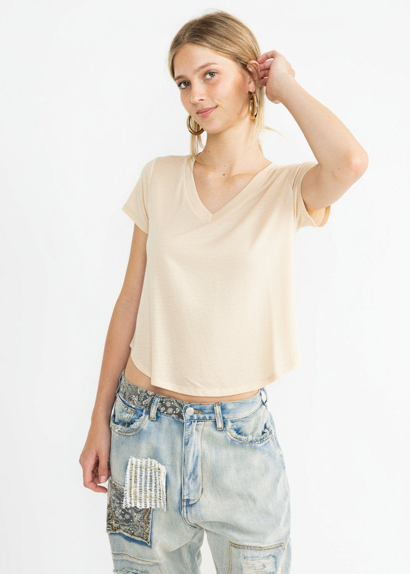 Woman wearing a beige top and light blue jeans on a white background