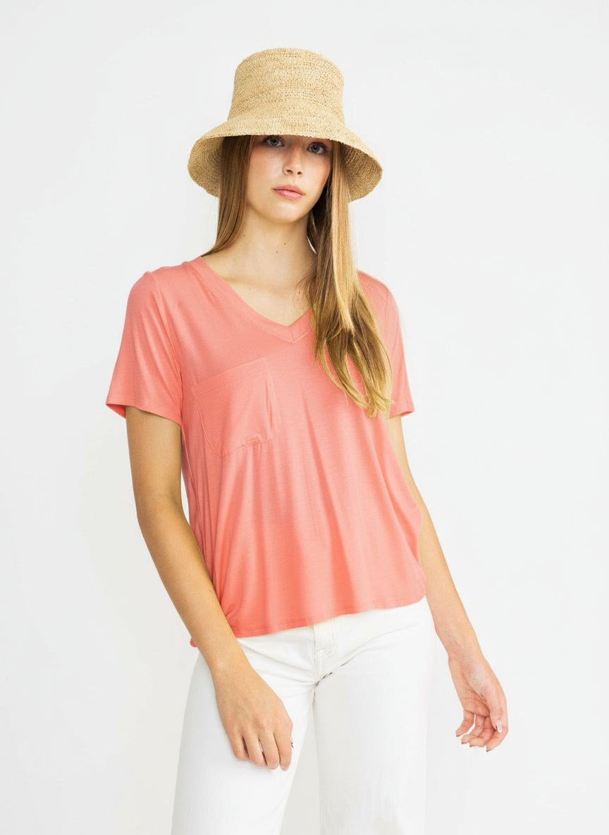 A female model wearing a yellow top and white pants, with a hat on her head.