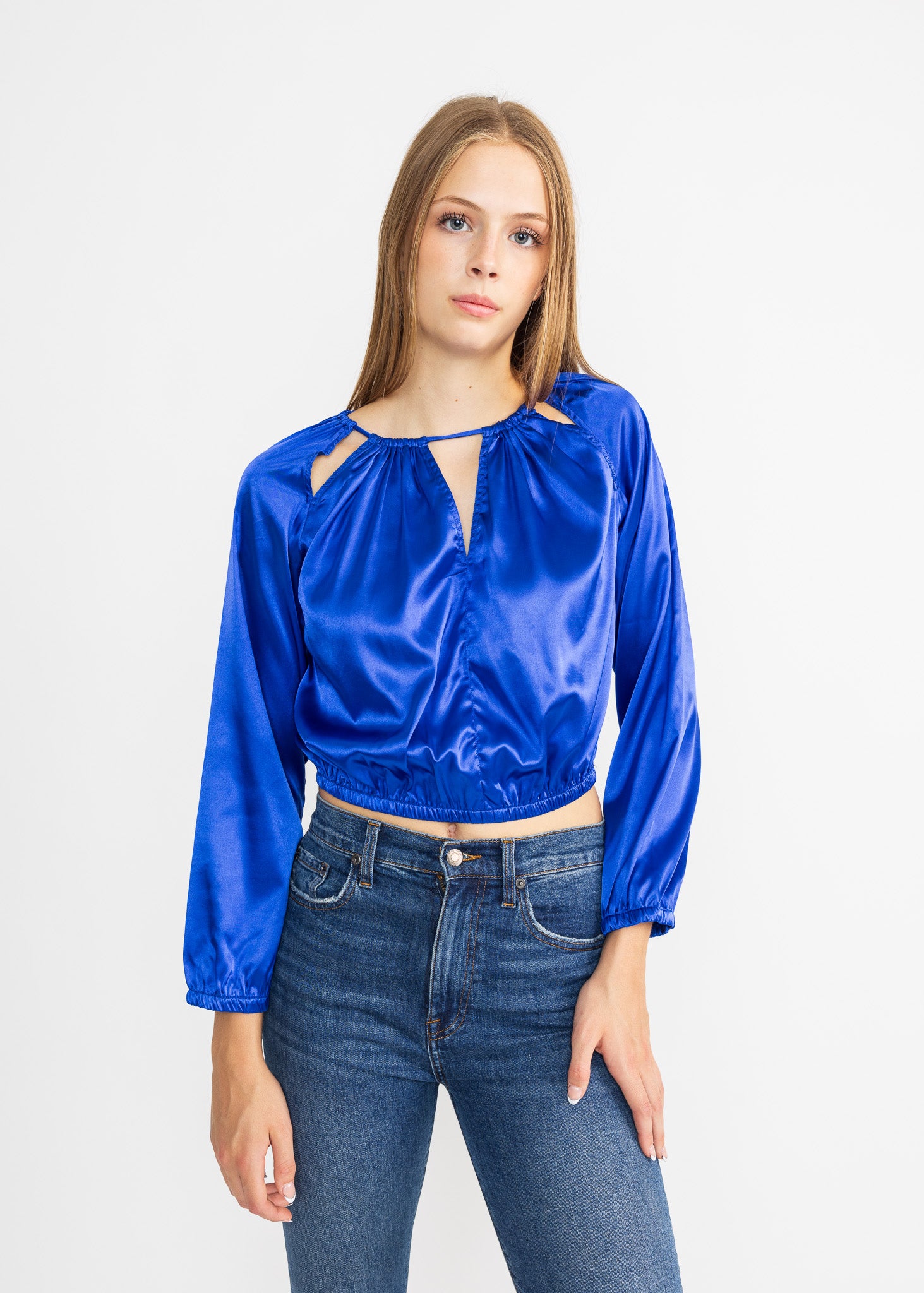 Woman wearing a blue satin top and jeans on a white background
