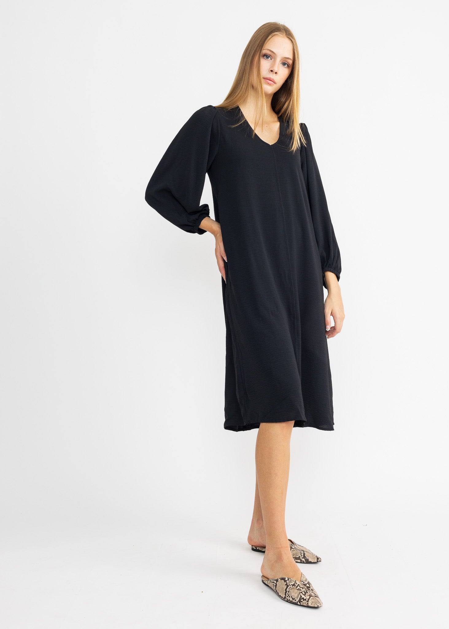 A woman wearing a black maxi dress with oversized puff sleeves and an elastic cuff design.