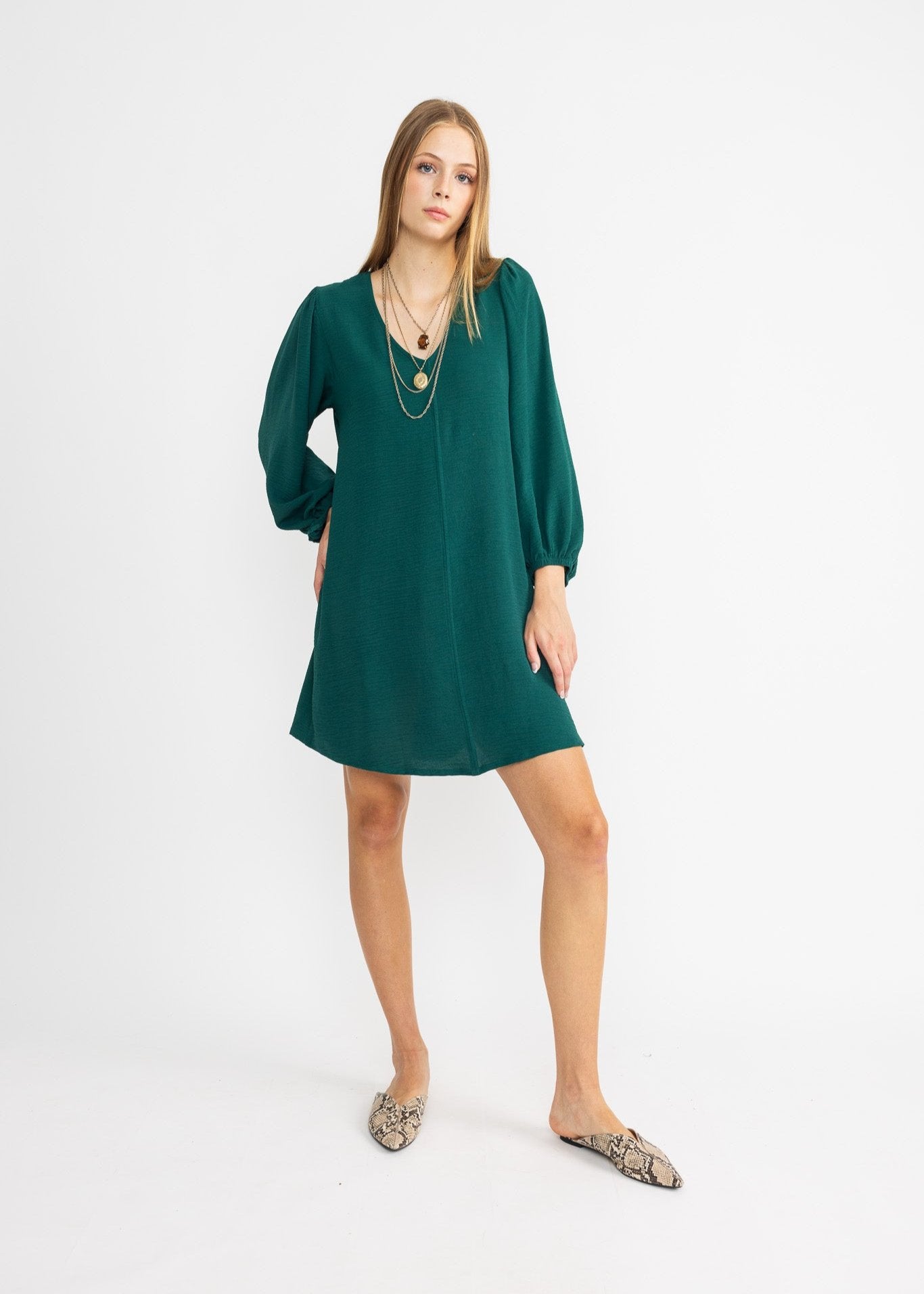 A woman in a green mini dress with balloon sleeves and an exciting, unique look.