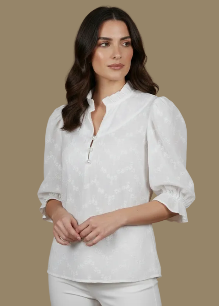 Woman wearing a white blouse with puffed sleeves against a beige background