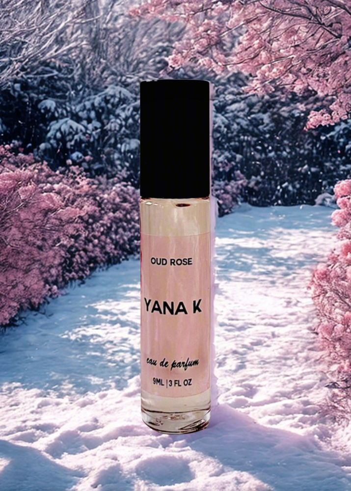 YANA K Oud Rose perfume bottle in a snowy landscape with pink cherry blossoms.