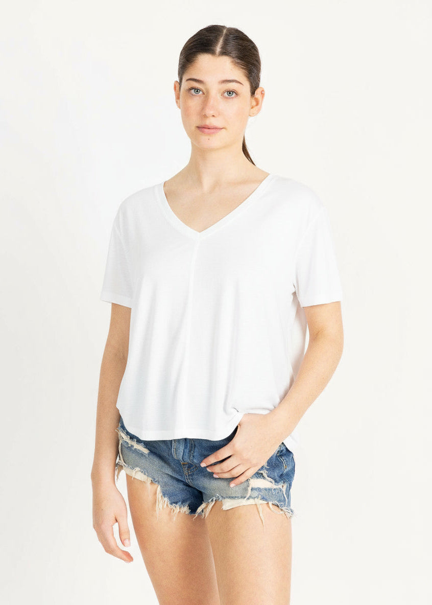 Casual woman in beige v-neck top and denim shorts.
