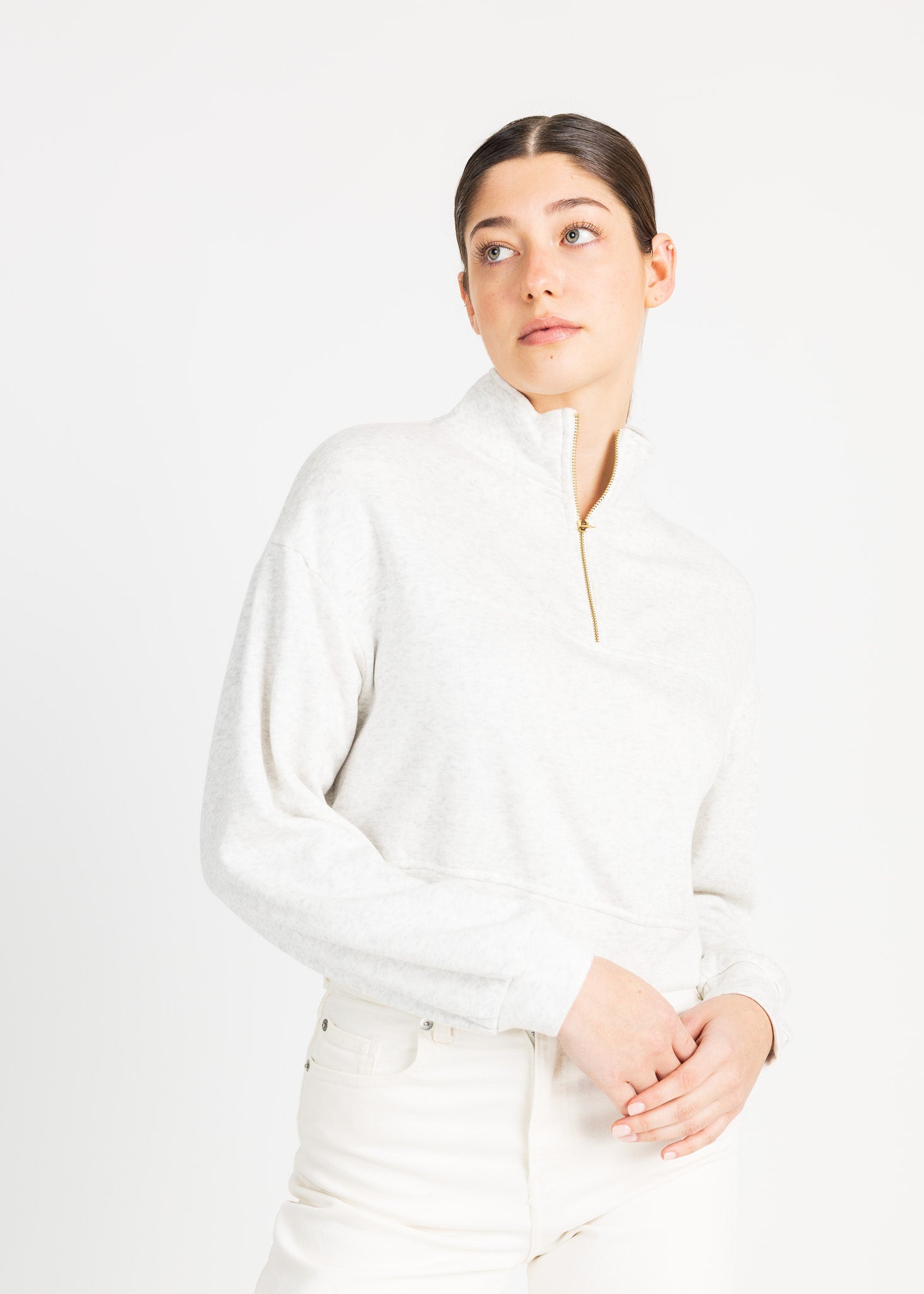 A woman wearing a high-necked, white fleece sweater poses against a plain white background.
