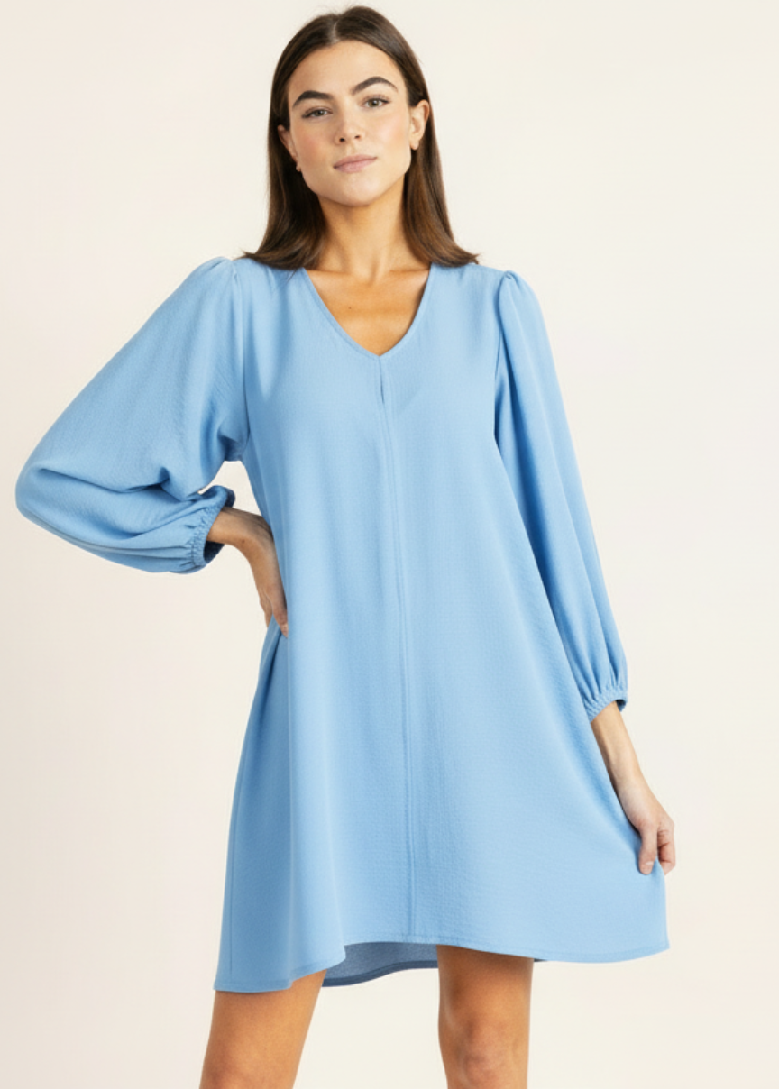 Woman wearing a light blue dress with balloon sleeves on a beige background