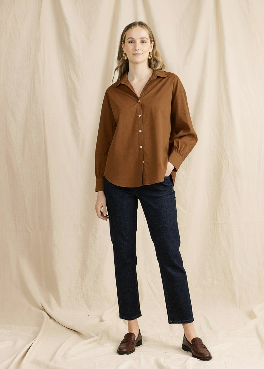 Woman wearing a brown shirt and black pants against a beige background