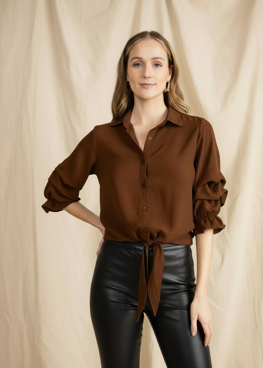 Woman wearing a brown blouse and black leather pants against a beige background