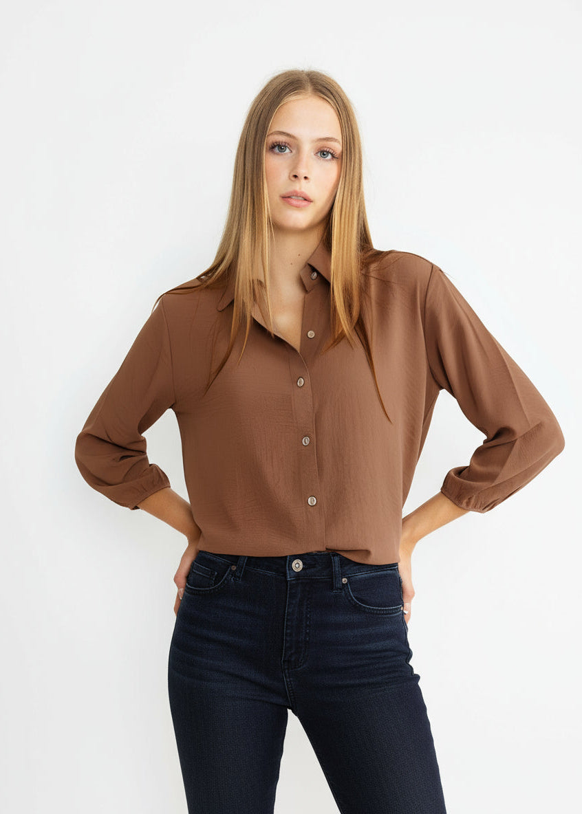 Woman wearing a brown blouse and blue jeans on a white background