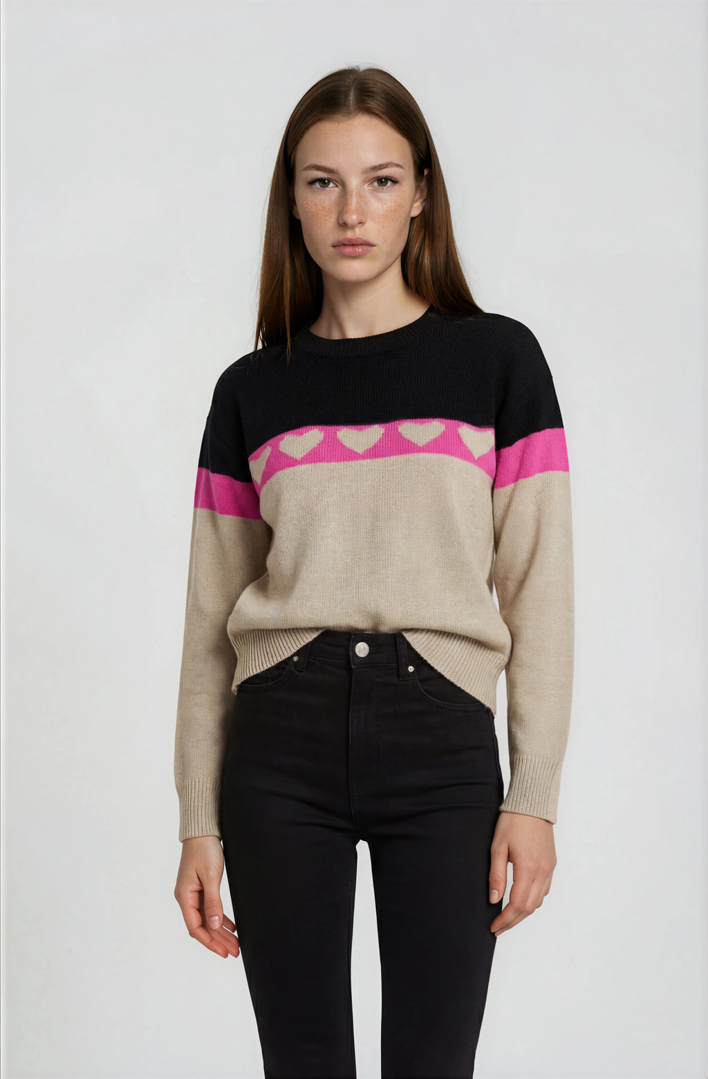 Woman wearing a black, pink, and beige sweater with a white background
