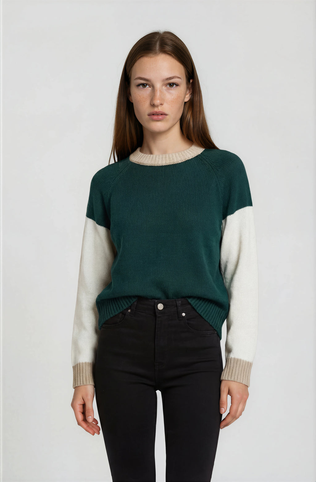 Woman wearing a green and beige sweater with black pants on a white background