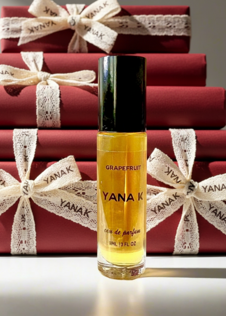 YANA K grapefruit perfume bottle with red gift boxes in the background
