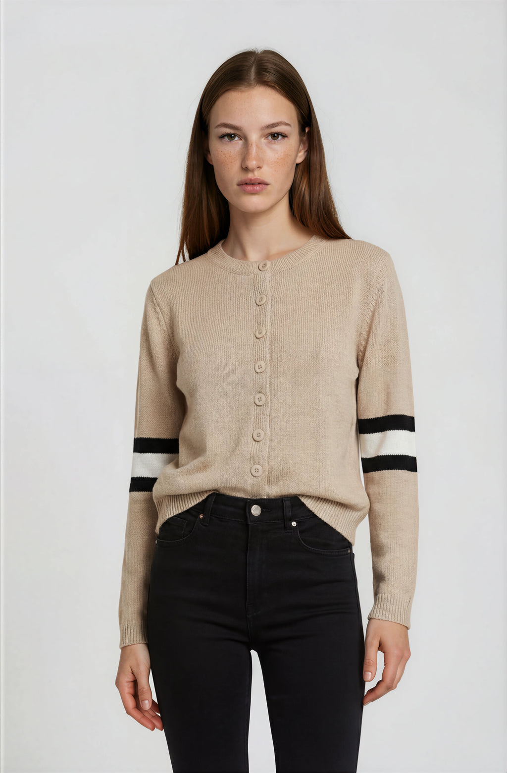 Woman wearing a beige cardigan with black and white stripes on a white background