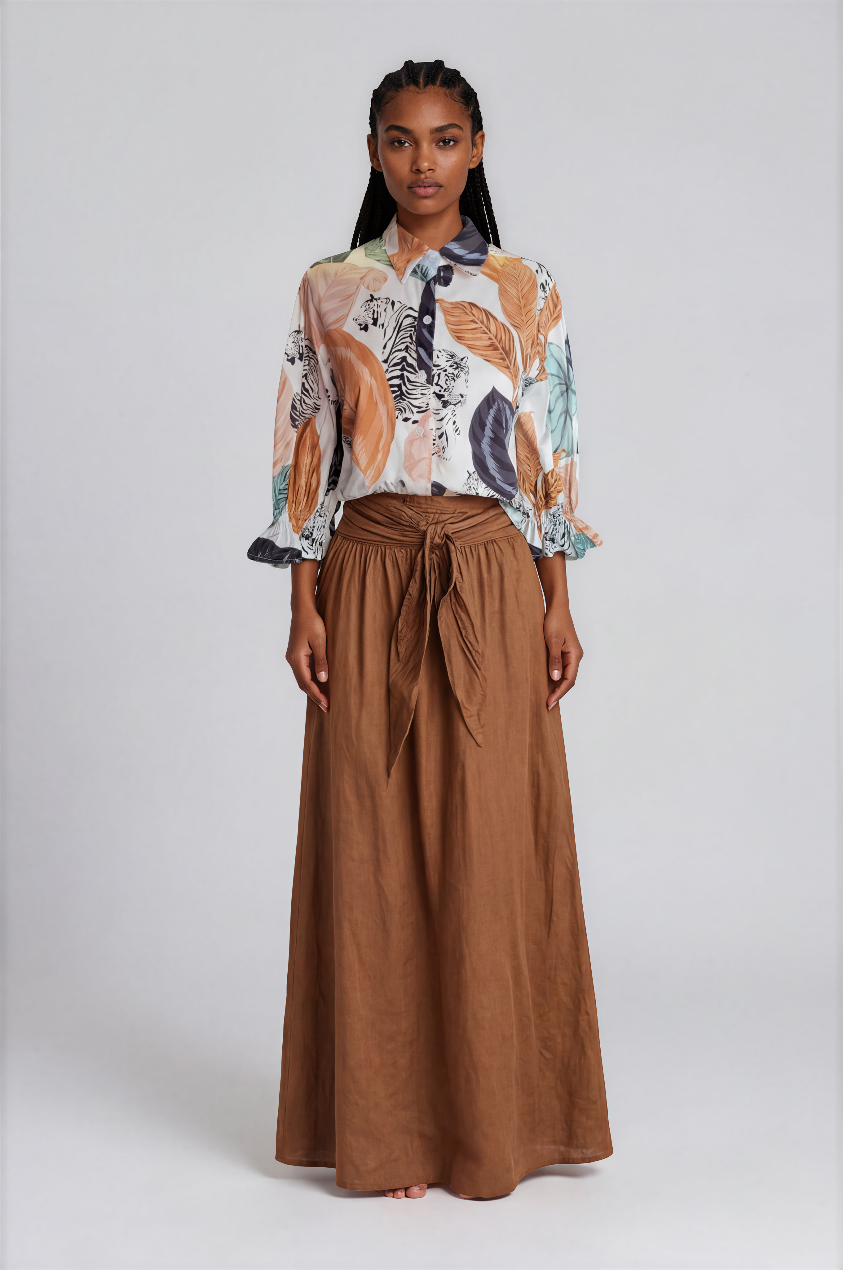 Woman wearing a patterned blouse and brown skirt on a white background