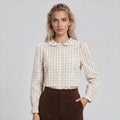 Woman wearing a checkered blouse and brown pants on a white background