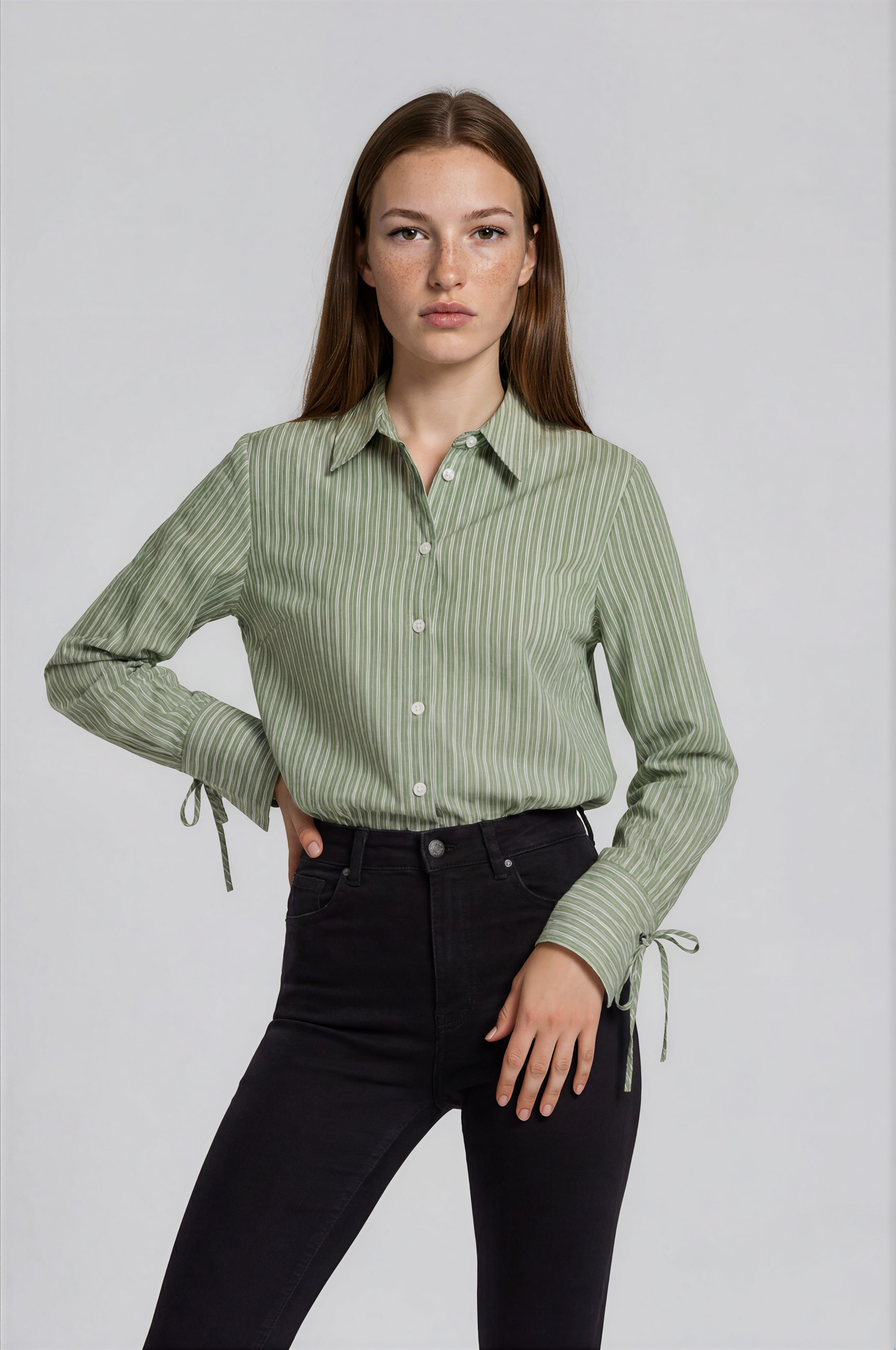 Woman wearing a green striped shirt and black pants on a white background