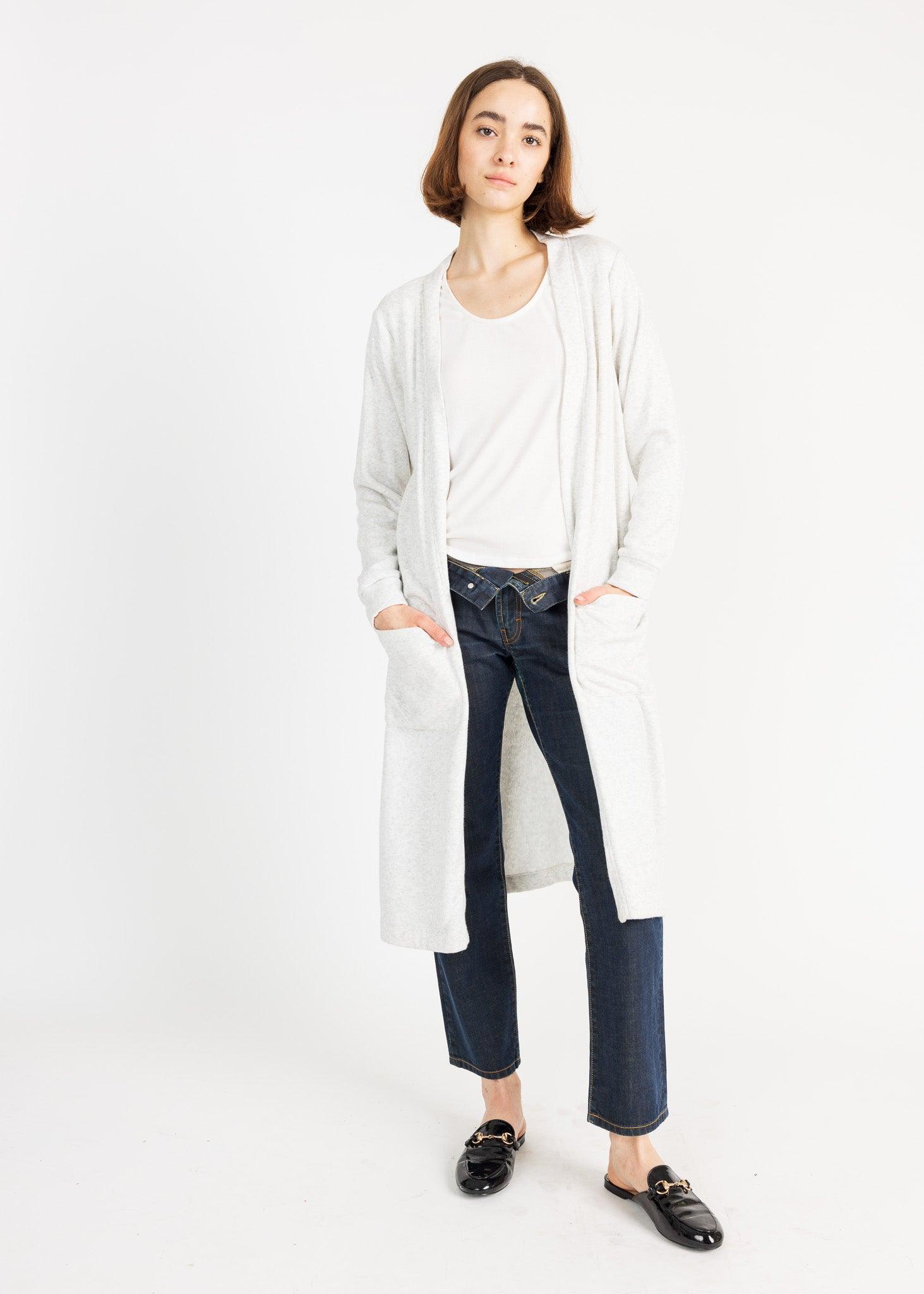 Stylish woman wearing a cozy cardigan sweater standing in front of a white background.